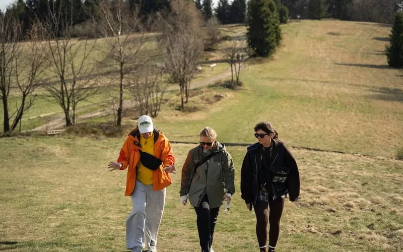 Three teammates walking down a grassy hillside trail