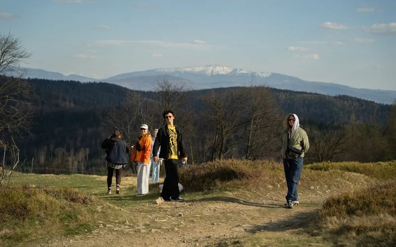 Hikers on a mountain trail with snow-capped peaks in the distance