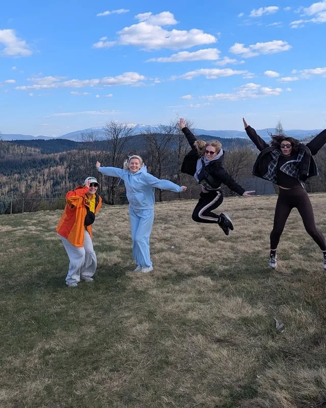 Four teammates jumping for joy on a hilltop meadow