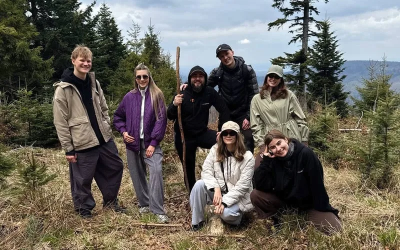 The whole team posing together in a forest clearing