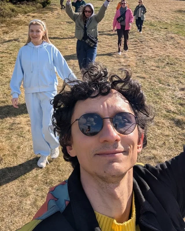 A teammate waving to the camera with the group walking behind